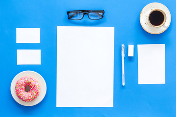 Come up with brand identity. Blank stationery for branding near coffee and donut on blue background top view mockup pattern