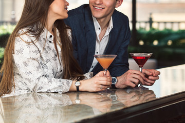 Man and woman enjoy the conversation on a date on bar counter drinking cocktails.