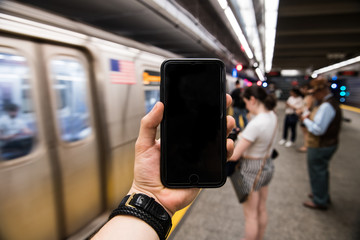 Man using cell phone holding in hand and showing touch screen on subway station in New York City. Empty cell phone screen in urban city setting. - 206923788