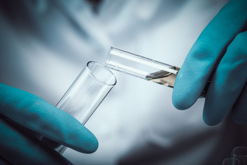 scientist dropping chemical liquid to flask with lab glassware background, Laboratory research...