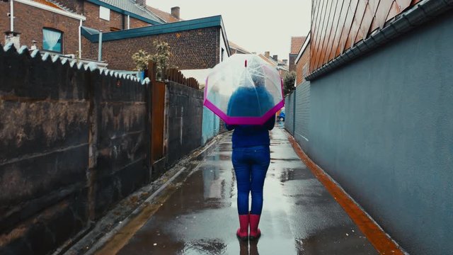 CINEMAGRAPH - SEAMLESS LOOP. Portrait of young girl standing with spinning umbrella in the rain at the street