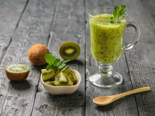 Freshly prepared smoothie of kiwi, Apple, mint and kiwi slices on the rustic table.