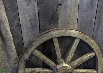 Wooden wheel of a cart leaning against a wooden wall