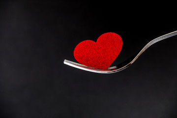 the red heart shape in silver fork , romance love dinning or health heart care concept