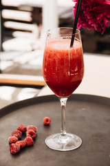 Glass of summer cocktail, summer drink, pink peony flowers on table