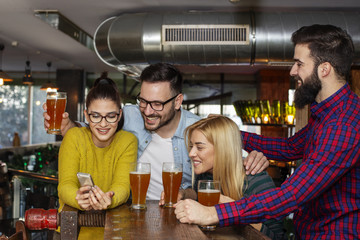 Group of four friends taking selfie by mobile phone on cafe and smile