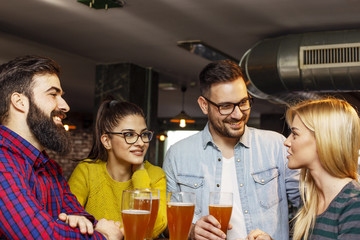 Group of four friends drinking beer and chat on lokal cafe