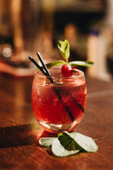 Delicious cocktail with ice cubes, cherry and straws in bar