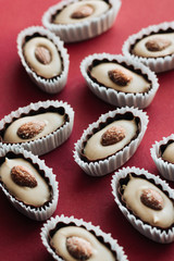 Flat lay of delicious praline sweets with almonds on red background