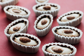 Flat lay of delicious praline sweets with almonds on red background