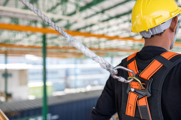 Construction worker wearing safety harness and safety line working on construction