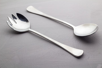 Salad server set isolated on grey texture background close up - Stainless steel cutlery
