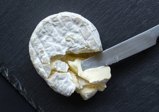 Camembert cheese on slate cheese board and knife - top view photo