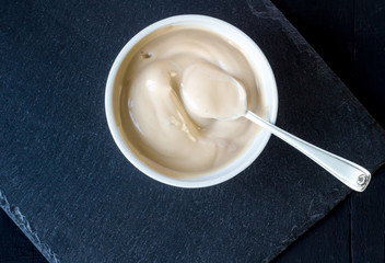 Yoghurt in white cup with silver spoon on black background - Creamy chocolate yogurt