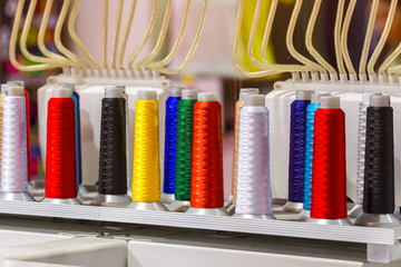 Colorful thread spools used in fabric and textile industry. The concept of sewing production.