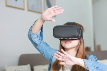 Young woman wearing virtual reality glasses at home.