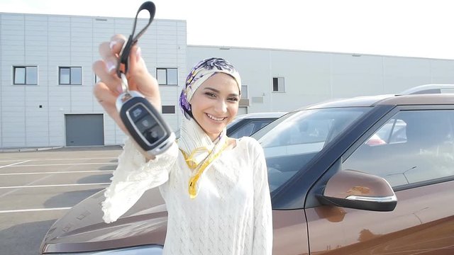 Muslim woman in hijab with car key outdoors