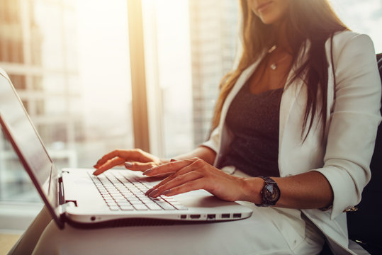 Woman Using Laptop On Her Lap Working In Modern Office