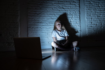 Sad young girl with laptop suffering bullying and harassment online. Cyberbullying, online gaming