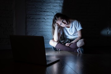 Sad young girl with laptop suffering bullying and harassment online. Cyberbullying, online gaming