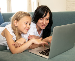Mother and daughter smiling and having fun together playing and surfing on the internet on a laptop