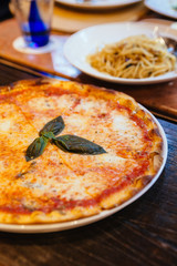 Margarita pizza topping with basil leaves served with oregano and chili powder.