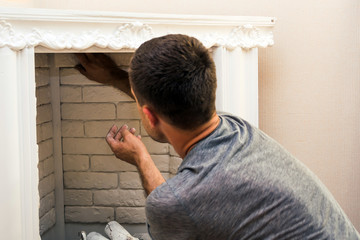 man glues decorative stone to the fireplace wall decorating it
