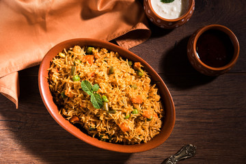 Indian Vegetable Pulav or Biryani made using Basmati Rice, served in terracotta bowl. selective focus