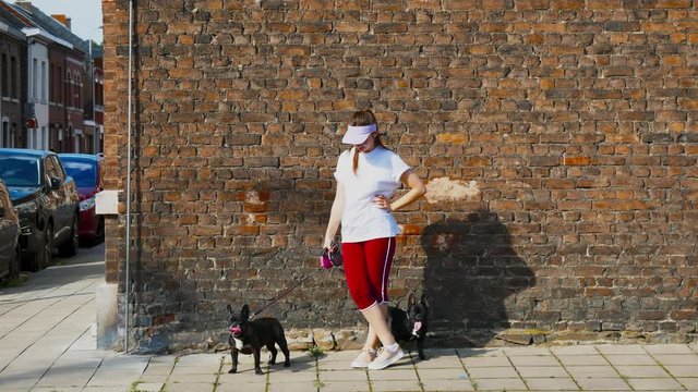 CINEMAGRAPH - SEAMLESS LOOP. Portrait of young Caucasian girl holding black french bulldog against brick wall
