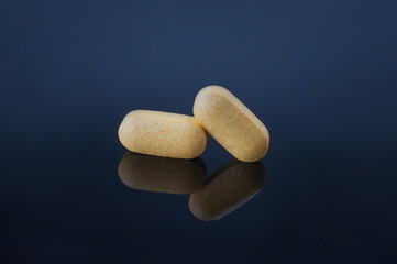 Medical pills with different size, shape and color on black glass table with reflection.Studio shot.