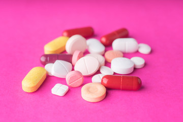 Medical pills and supplement capsules on pink background.Close up studio shot.