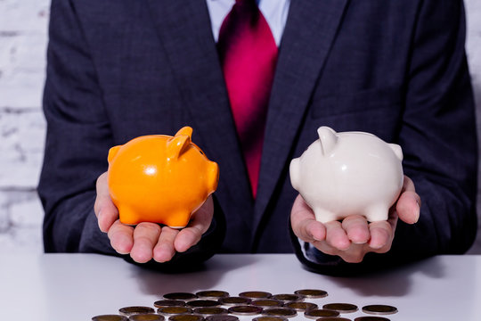 Businessman making a comparison and difference between each money piggy bank - finance issue comparison concept.