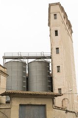 Depósitos cilíndricos y metálicos al lado de una torre estrecha.