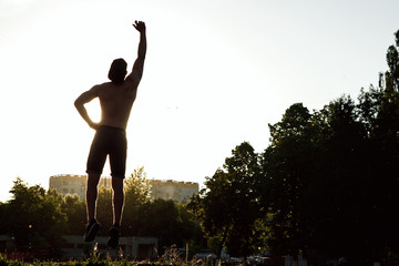 silhouette of a man at sunset, hands raised, victory, joy