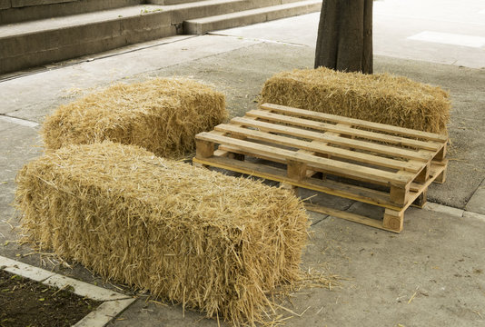 Mesa y asientos con elementos naturales como un pal&eacute; y unas balas de paja.