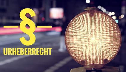 Baustellenlampe und Verkehr bei Nacht mit der Aufschrift § Urheberrecht zur Verdeutlichung von Urheberrechtsverstößen