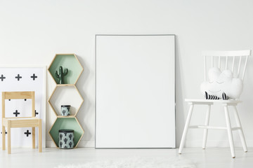 White and wooden chair in kid's room interior with mockup of empty poster. Real photo