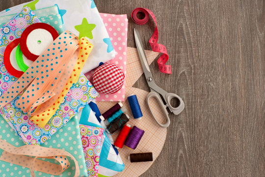 Different items for sewing clothes. Cloth, tailor's scissors. millimeter paper, ribbons, a pillow for needles, threads are needed for sewing clothes. View from above.