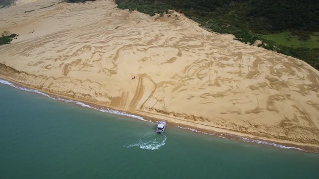 Drone shot of a boat at sand dunes in Hokianga, New Zealand