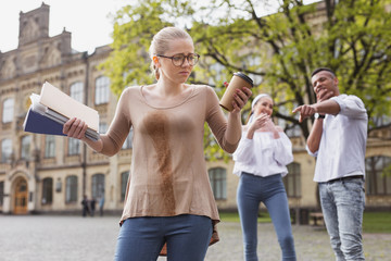 Spilling drink. Blonde-haired student in glasses feeling awful after spilling her drink on her shirt