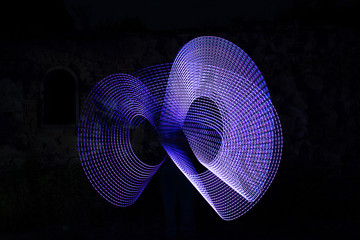 Blue electric light painting, long exposure photography, ripples and waves pattern against a black background