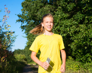 Fototapeta premium Runner teen girl with headphones and smart phone outdoors. Happy beautiful sports fitness teenager girl living healthy active lifestyle.