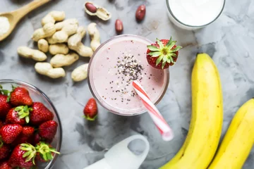 Papier Peint photo Milk-shake A glass of strawberry banana smoothie among the ingredients for its cooking - strawberries, bananas, milk, yogurt, chia seeds, sesame and peanuts. Healthy eating breakfast. Top view, flat lay