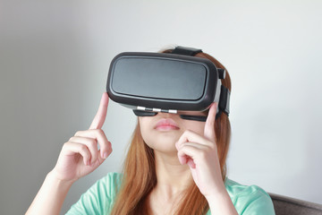 Young woman wearing virtual reality glasses at home.