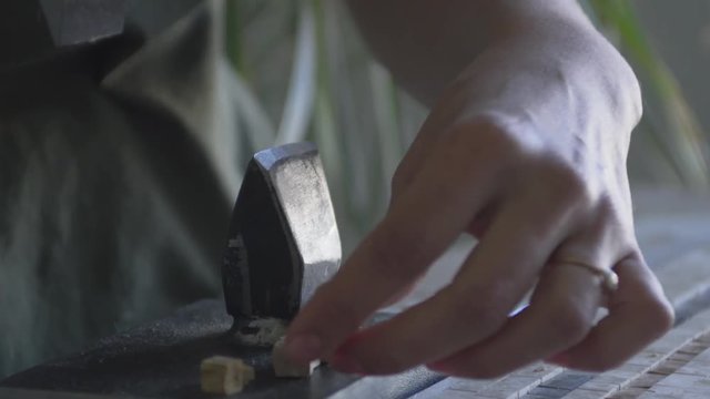 Master with the help of a hammer and anvil makes a part for making panels video closeup