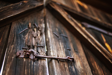 Fototapeta na wymiar Old wooden gate closed on a rusty lock hook, texture