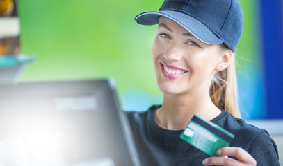 Attractive young woman working at a cash desk with a credit card