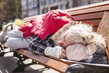 Housing crisis. Aged homeless man resting on the street while not having a place to it
