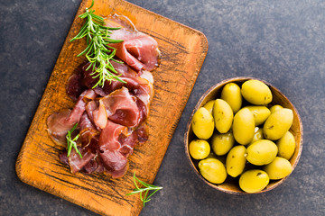 Prosciutto with rosemary on a black background.