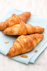 Tasty buttery croissants on old wooden table.